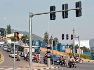 Busy urban intersection with motorcycles cars and a bus waiting at a red light construction fencing and hills in the background